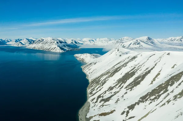 La costa montuosa del mare coperta di neve in un tempo soleggiato . — Foto Stock