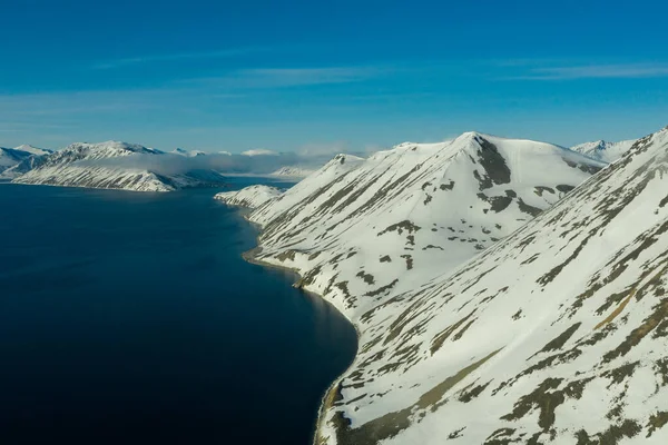 Dağlık deniz kıyıları güneşli bir havada karla kaplıydı.. — Stok fotoğraf