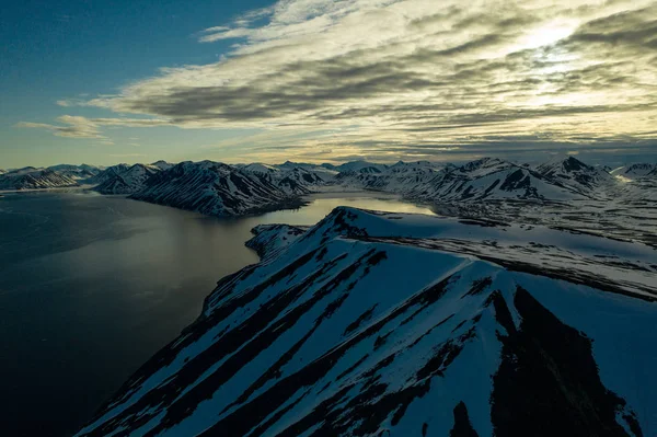 La costa del mar montañoso está cubierto de nieve con el sol la —  Fotos de Stock