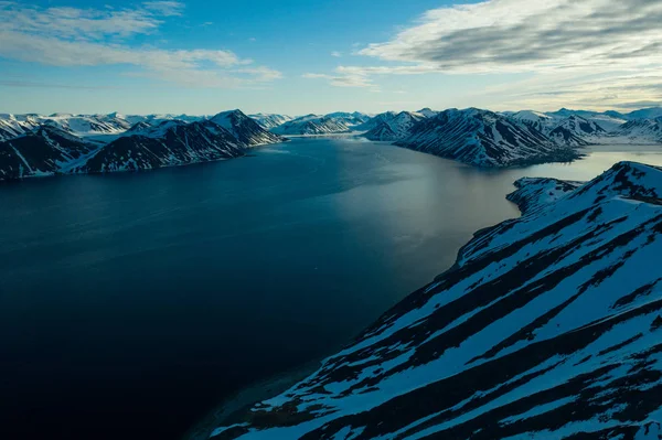 Den bergiga kusten täckt med snö i soligt väder. — Stockfoto