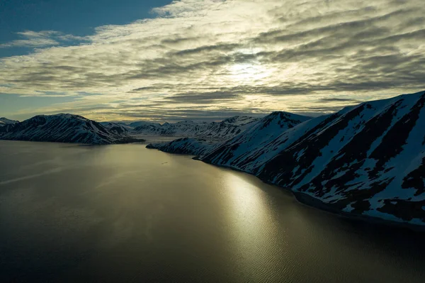 A costa montanhosa do mar é coberta de neve com o sol — Fotografia de Stock