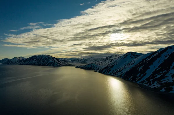 La costa montuosa del mare è coperta di neve con il sole — Foto Stock