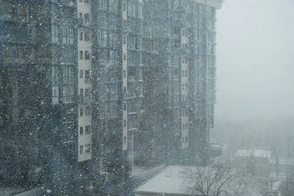 雪在风中飘落 在一座城市房屋的背景下形成了暴风雪 在一幢多层楼房的背景上 冬季的降雪 背景很模糊 — 图库照片