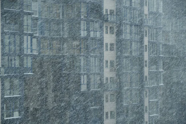 雪在风中飘落 在一座城市房屋的背景下形成了暴风雪 在一幢多层楼房的背景上 冬季的降雪 背景很模糊 — 图库照片