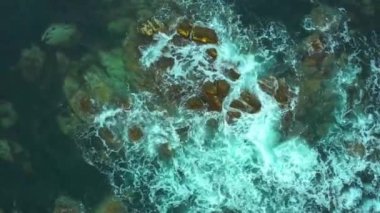 Kıyı taşlarında akan ve köpüren deniz dalgaları.