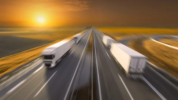 Four trucks in motion blur on the empty highway at sunset — Stock Photo, Image