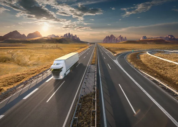 Один белый грузовик на шоссе на идиллическом закате — стоковое фото