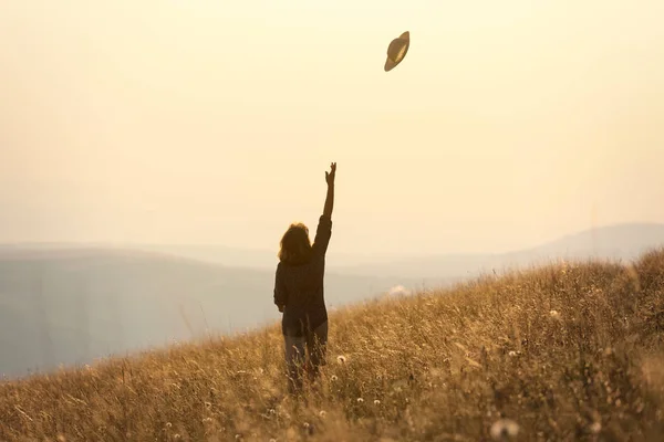 Девушка путешествует по горам и веселится на идиллическом поле на солнце — стоковое фото