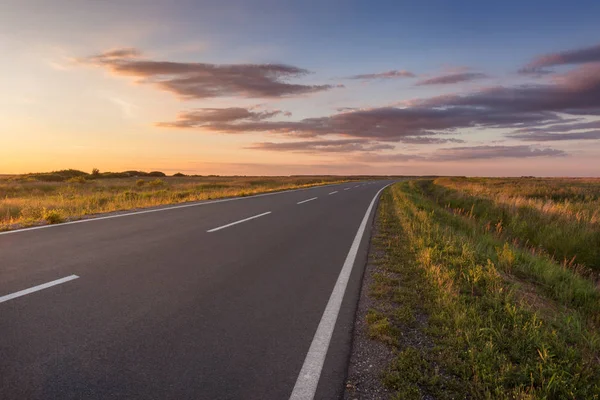 Estrada de asfalto curvada em planície ao pôr do sol idílico — Fotografia de Stock
