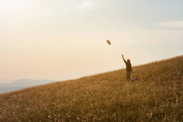 Девушка в горах веселится на огромном идиллическом поле на закате — стоковое фото