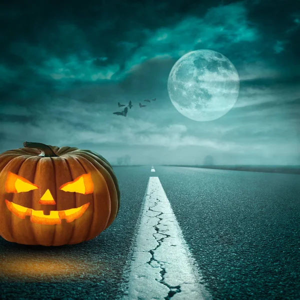 Espeluznante calabaza de Halloween en camino de asfalto a la luz de la luna — Foto de Stock