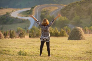 Eller yukarı gün batımında pastoral alan genç kadınla