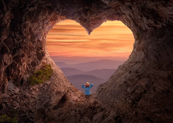 Woman in heart shape cave towards the vast landscape — Stock Photo, Image