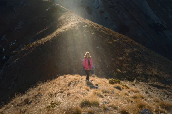 Женщина-турист спускается с высоких горных вершин — стоковое фото