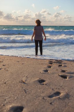 Güneş, sahilde duran yalnız kadın