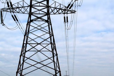 Yüksek voltajlı elektrik hattı. Direğin çelik yapısı. Kablolar, yalıtıcılar mavi gökyüzüne karşı.