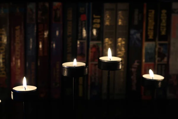 Candle flame on blurred background from books. Book shelf in the library.