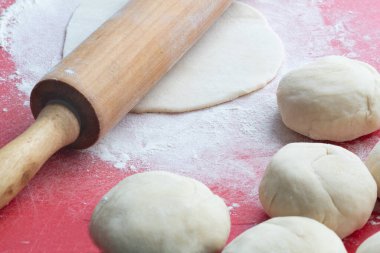 Hamurdan tortilla pişirme, ahşap raptiye ve masada hamurdan toplar..