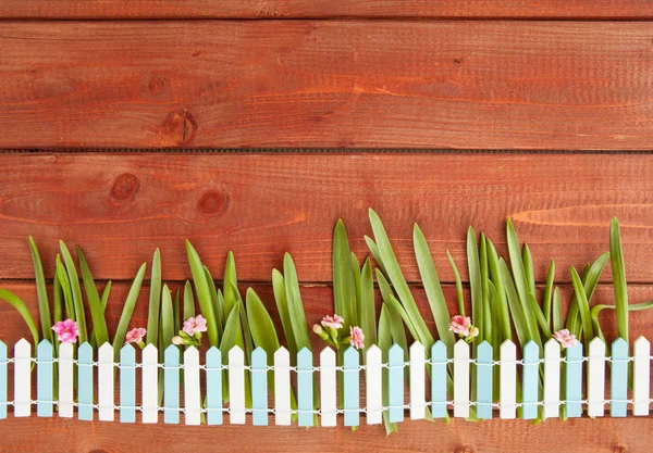 Pequeña cerca de piquete sobre fondo de madera — Foto de Stock