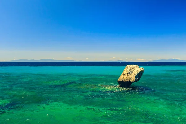 De rotsachtige kust met uitzicht op de azuurblauwe zee in warme summe — Stockfoto