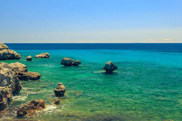 De rotsachtige kust met uitzicht op de azuurblauwe zee in warme summe — Stockfoto