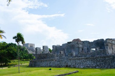 Ruins of ancient Tulum. Architecture of ancient maya. View with temple and other old buildings, houses. Blue sky and lush greenery of nature. travel photo. Wallpaper or background. Yucatan. Mexico.