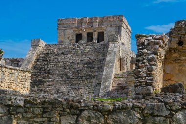 Ruins of ancient Tulum. Architecture of ancient maya. View with temple and other old buildings, houses. Blue sky and lush greenery of nature. travel photo. Wallpaper or background. Yucatan. Mexico.