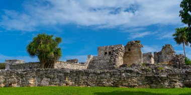 Ruins of ancient Tulum. Architecture of ancient maya. View with temple and other old buildings, houses. Blue sky and lush greenery of nature. travel photo. Wallpaper or background. Yucatan. Mexico.