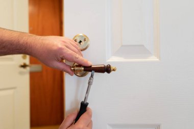 Beyaz kapı kilidini tornavidayla tamir eden bir adam. Kapıları tamir etmeye yakın çekim.