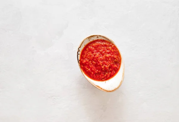 Hot chili pepper sauce paste harissa. Adjika on a white background. Traditional Tunisia, Georgian and Arabic cuisine. Homemade rose harissa in a bowl.