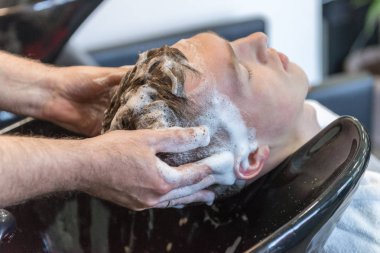 Kuaför dükkanında bir saç kesimi üzerinde genç adam