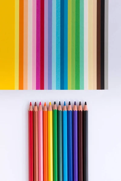 Lápices de colores y papel de colores sobre un fondo blanco — Foto de Stock