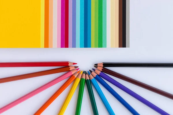 Lápices de colores y papel de colores sobre un fondo blanco — Foto de Stock