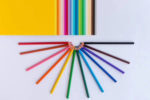 Lápices de colores y papel de colores sobre un fondo blanco — Foto de Stock