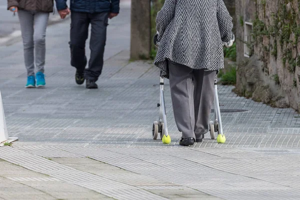 Anciana con un dispositivo sobre ruedas para dar un paseo por la calle Fotos de stock