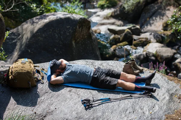 Turist med en ryggsäck som vila liggande på en sten — Stockfoto
