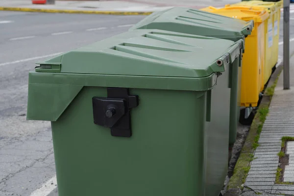 green and yellow plastic garbage can in the street