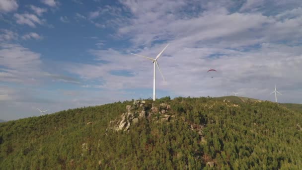 Paracaidista Vuela Sobre Generador Viento Cima Una Montaña Cubierta Árboles — Vídeos de Stock