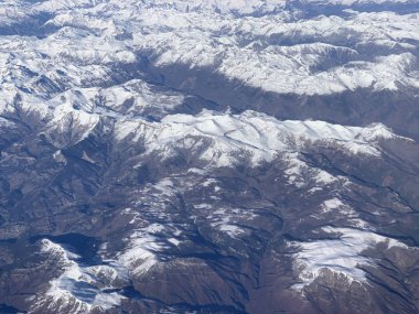 Bir uçağın lombozundan karlı dağların manzarası