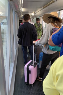 İnsanlar havaalanından uçağa binmek için sırada bekliyorlar. 