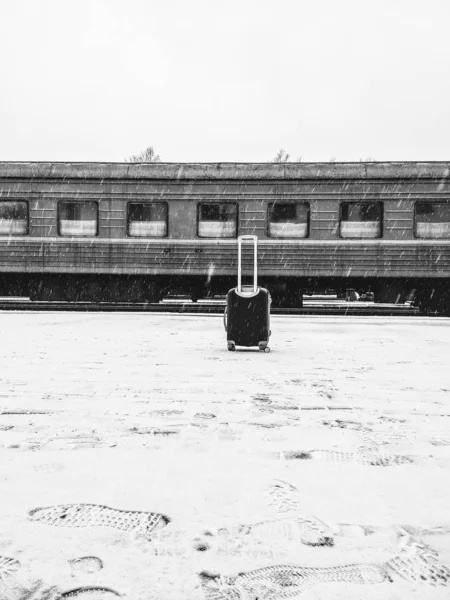 Anreise mit der Bahn. Ein Koffer steht bei Winterwetter neben dem Zug — Stockfoto