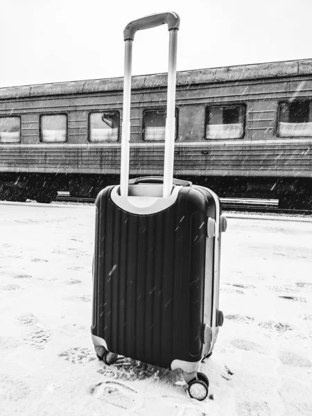 Podróż pociągiem. Walizka stoi w pobliżu pociągu w zimie weat — Zdjęcie stockowe