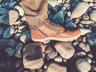 Nehir kenarındaki çakıl taşlarının üzerinde insan bacakları.