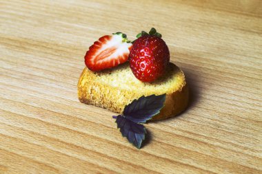 Çilekli ve fesleğenli Rusklar tahta bir tahtanın üzerinde yatar. İncompa