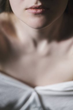 Beyaz gömlekli güzel bir mankenin portresi. Vücudun narin dişi kısmı açık. Çıplak boyun. Dudaklara odaklan.