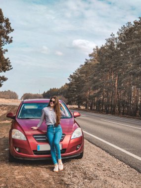 Neşeli kız koşan arabanın esintisinin tadını çıkarıyor. Arabanın yanındaki kız.