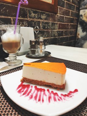 Cheesecake dilimi, arka planda peynirli kek. Tatlı çatalıyla beyaz bir tabakta lezzetli bir pasta dilimi