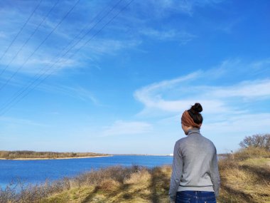 Bir kadın sırtı kameraya dönük durur, nehre bakar, doğa. Bahar için reklam alanı