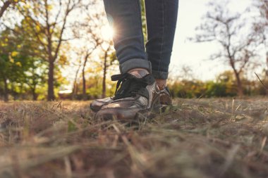 Çimlerin üzerinde atlet bacakları. Spor konsepti. Aktif atlet yaşam tarzı. Parkta batan güneşin arka planında ayaklar