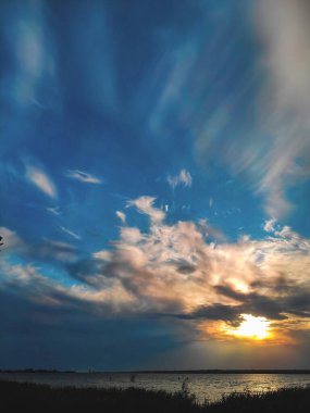 Gün batımında bulutlu bulutlu bulutlar ılık gün batımında aydınlık, renkli günbatımı gökyüzü akşam güneşiyle aydınlanan dramatik gökyüzü bulutları. Gün batımında köy yolu